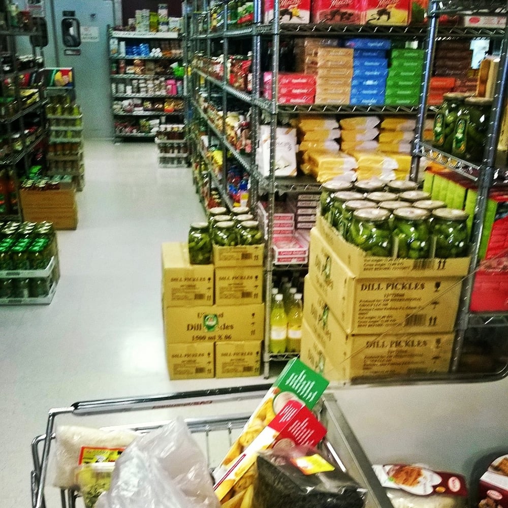 Grocery aisle stocked with jars of dill pickles and imported packaged goods